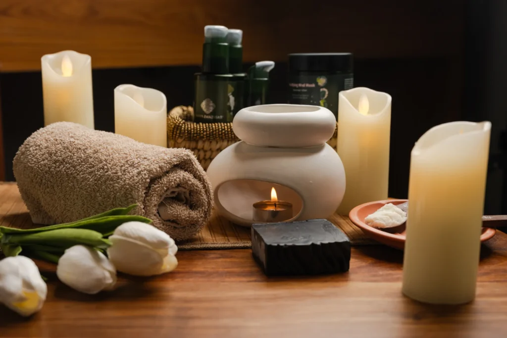 Candles, an oil burner, rolled towel and tulips on a wooden table