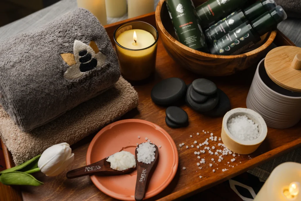 Therapist setting out oils, hot stones and towels on a candlelit tray