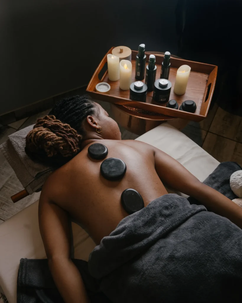 Hot stones placed along a guest's back, with a tray of oils behind